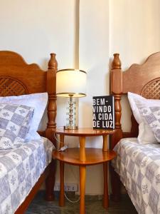a bedroom with two beds and a table with a lamp at Quarto Privativo na AvBeira mar - Apto familiar in Fortaleza
