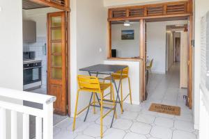 a kitchen with a table and two yellow stools at Appartement Jade in Les Trois-Îlets