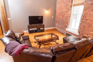 a living room with a leather couch and a tv at Georgia Street 4 Bedroom Condo Downtown in Indianapolis