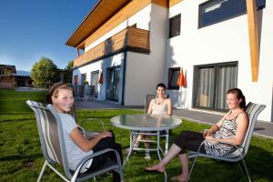 three women sitting around a table outside of a house at Apartments in Flachau - Salzburger Land 368 in Flachau