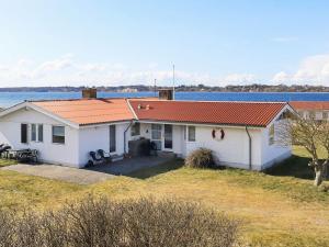 a white house with an orange roof next to the water at 10 person holiday home in Farsø-By Traum in Farsø