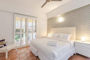 a white bedroom with a white bed and a desk at The Hill Villa 2 in Port Douglas +14 photos