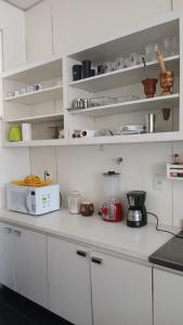 a kitchen with white cabinets and a microwave on a counter at Hostel Triplo J e Guest House in Salvador