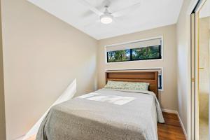 a small bedroom with a bed and a window at Amara Grove Brisbane Cottage - Come Home to Calm in Eatons Hill