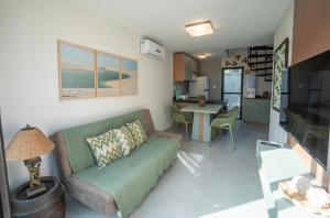 a living room with a green couch and a kitchen at Casa 12 do Paraíso - Atins in Atins