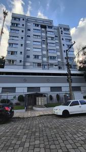 a white car parked in front of a large building at Apartamento residencial vert in Bento Gonçalves