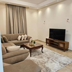 a living room with a couch and a television at Modern Hotel-Style Apartment in El Alamein