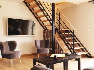 a living room with a staircase and two chairs and a table at Charmant gîte 80m² proche frontière belge, jardin privatif, terrasse, tout inclus, 2 chambres, WiFi - FR-1-510-133 in Sebourg
