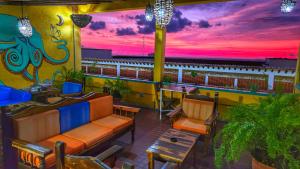 a patio with a couch and chairs and a sunset at Casa Kraken Hostel in Puerto Vallarta