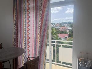 フォール・ド・フランスにあるAppartement Coquelicot à 5 min du CENTRE VILLE FDFのバルコニーの景色を望む窓付きの客室です。