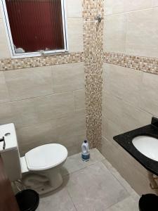 a bathroom with a toilet and a sink at Meu Encanto Itanhaém SP in Itanhaém