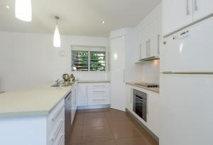 a white kitchen with white cabinets and a sink at Roya on Mission - Beachfront - Wongaling - Family in Mission Beach