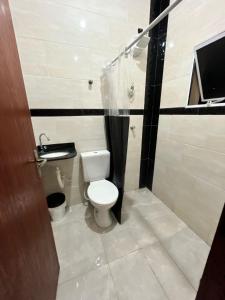 a bathroom with a toilet and a television in it at Meu Encanto Itanhaém SP in Itanhaém