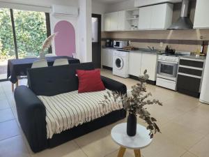 Una sala de estar con un sofá y una cocina. en Casa Rubí - Encantador apartamento en Mendoza - Cochera privada y seguridad permanente, en Guaymallén