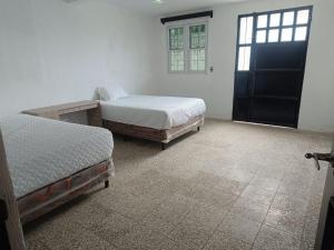 a bedroom with two beds and a table and a door at Apartamento con 5 camas in Quetzaltenango