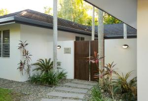 a white house with a wooden door and some plants at Roya on Mission - Beachfront - Wongaling - Family in Mission Beach