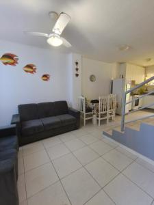a living room with a black couch and a kitchen at Sobrado confortável a uma quadra do mar. in Matinhos
