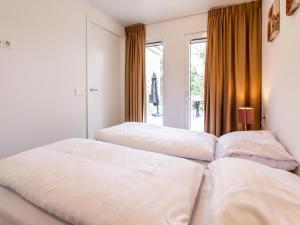 two white beds in a room with a window at Holiday home with gas fireplace & bath in Bemelen