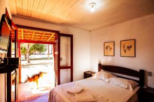 a bedroom with a bed and a dog looking out the door at Hotel Fazenda Portal da Canastra in Zogaias +110 photos