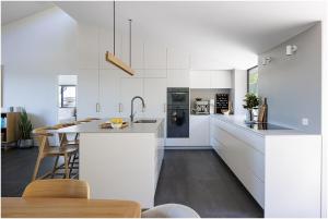 a kitchen with white cabinets and a kitchen island at Beach, Golf & Luxury! Sunrise to Sunset Views in Forster