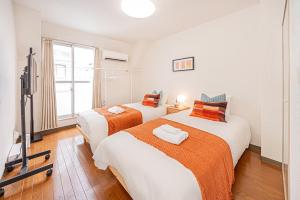 two beds in a room with a tv at Shinjuku Wind Apartment • Cozy Retreats in Tokyo