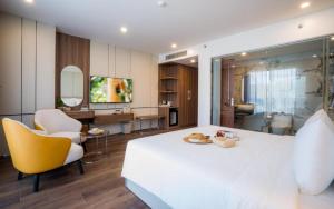 Un dormitorio con una gran cama blanca y un baño. en Danitel Halong, en Ha Long