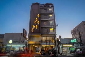 a tall building with yellow triangles on it on a city street at Yellow Star Gejayan Hotel in Yogyakarta