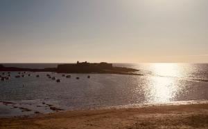 a body of water with a castle in the background at STUDIO BORD DE MER LOMENER in Ploemeur