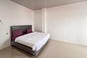 a bedroom with a large bed with purple pillows at RedDoorz at Ideal Home Banjarmasin in Banjarmasin
