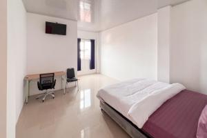 a white bedroom with a bed and a desk at RedDoorz at Ideal Home Banjarmasin in Banjarmasin +16 photos