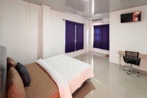 a bedroom with a bed and a desk and two windows at RedDoorz at Ideal Home Banjarmasin in Banjarmasin