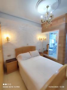 a bedroom with a large white bed and a chandelier at Dar NABIL in Chefchaouen