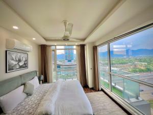 a bedroom with a bed and a large window at Elysium Tower Premium Serviced Apartments Facing Centaurus Mall Islamabad in Islamabad