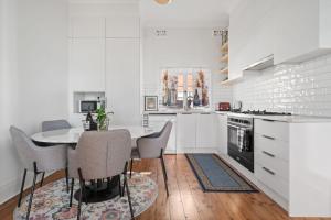 cocina blanca con mesa y sillas en Sweet Stewart - Walk to CBD Convenient & Cosy, en Bathurst
