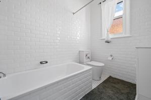Un baño blanco con bañera y inodoro. en Sweet Stewart - Walk to CBD Convenient & Cosy, en Bathurst 9 fotos más
