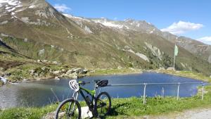 a bike parked next to a lake in the mountains at Hotel Garni Valülla in Ischgl