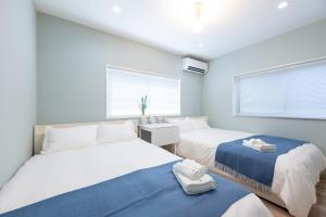 two beds in a room with two windows at 長期割がお得 最大8名 2BR 55平米 東京駅電車10分 TDR スカイツリー好アクセス 駐車場予約 送迎有 HOTEL DREAM MUSIC Tōyōchō pastel in Tokyo