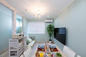 a living room with a table and a television at 長期割がお得 最大8名 2BR 55平米 東京駅電車10分 TDR スカイツリー好アクセス 駐車場予約 送迎有 HOTEL DREAM MUSIC Tōyōchō pastel in Tokyo