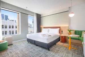 a hotel room with a bed and a desk at Holiday Inn Melbourne Bourke Street Mall by IHG in Melbourne +115 photos