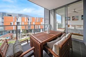 an apartment balcony with a wooden table and chairs at Little Bay Haven-Stylish Coastal Apartment in Sydney