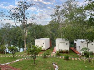 two white buildings in a field with trees at Muengtaboon Camping Park in Thung Yai