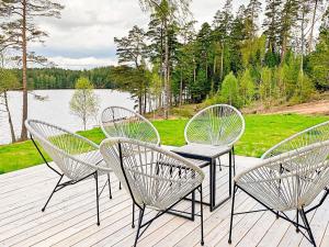 three chairs and a table on a deck with a lake at 4 star holiday home in Håcksvik in Håcksvik