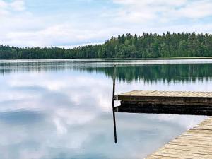 a dock on a lake with trees in the background at 4 star holiday home in Håcksvik in Håcksvik
