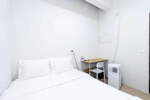 a white bedroom with a bed and a table at XX The Hidden Khaosan Road เดอะ ฮิดเด้น ถนนข้าวสาร - รามบุตรี in Bang Bua Thong Railway Station