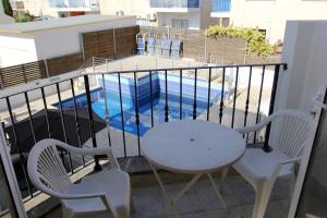 Un balcón con mesa y sillas y una piscina. en Villa Christina, en Pafos
