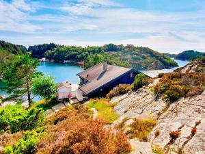 a house on a hill next to a body of water at 6 person holiday home in Urangsvåg in Steinsbø