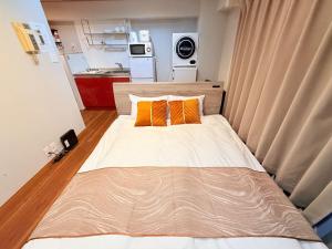 a small bedroom with a bed with two orange pillows at NC-302Yamanote Line shinjuku 高田馬場 5mins walk Hostel! 高速Wi-fi! Waseda in Tokyo