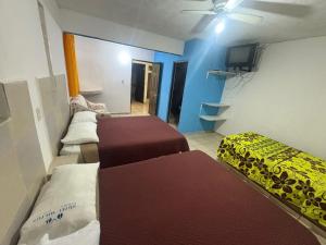 ein Zimmer mit drei Betten und einem Deckenventilator in der Unterkunft Hospedaje Ferchitos in Sofía