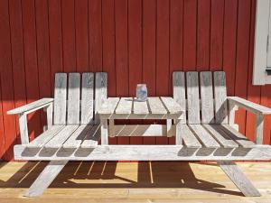 a wooden bench with a table in front of a red wall at 4 person holiday home in HEMSE in Hemse
