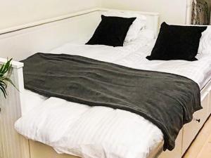 a bed with white sheets and black pillows on it at 4 star holiday home in Löddeköpinge in Löddeköpinge